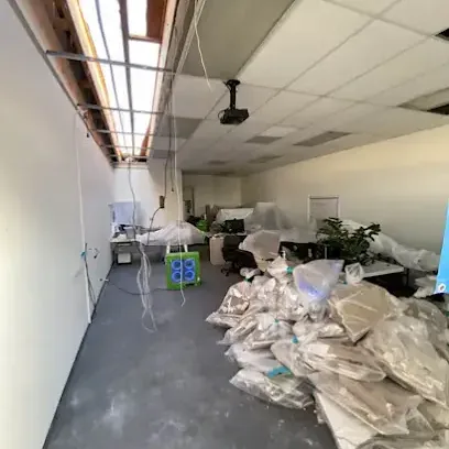 Office with wet ceiling tiles pulled down and debris bagged on the floor